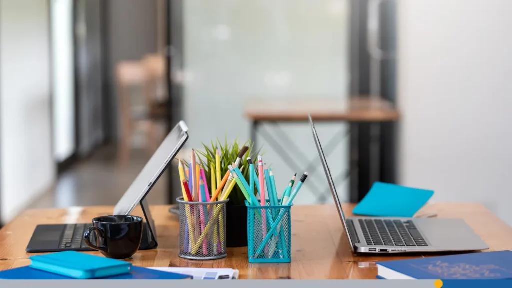 Two computers and office supplies at a desk