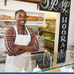 Owner behind the counter of sandwich bar with arms crossed