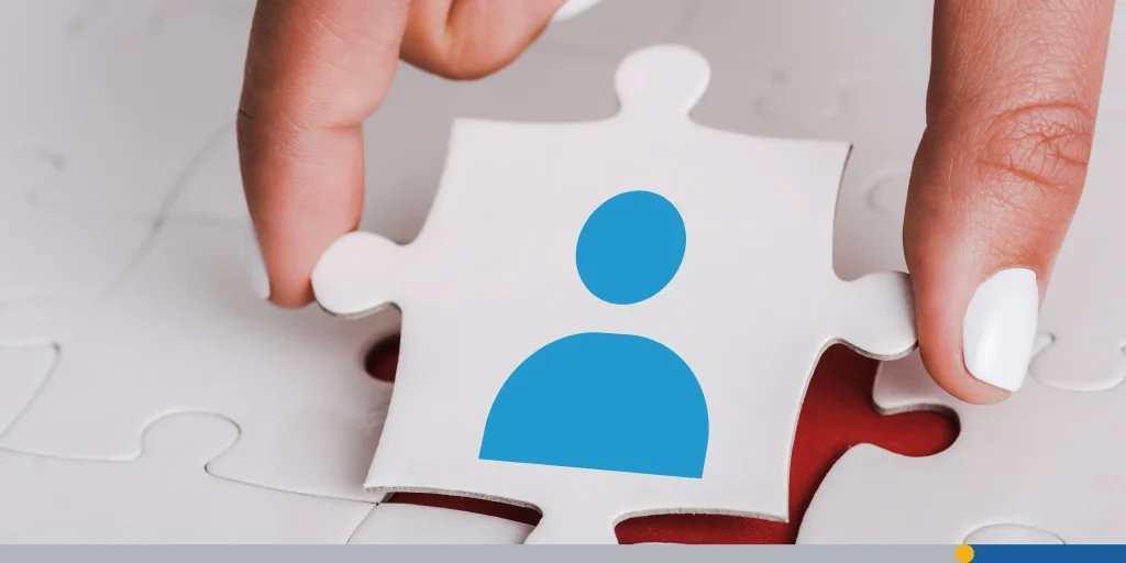 Close up of woman holding white jigsaw with blue human icon near connected puzzle pieces