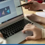 Hands of creative designers by laptop display with sketch of geometric figures