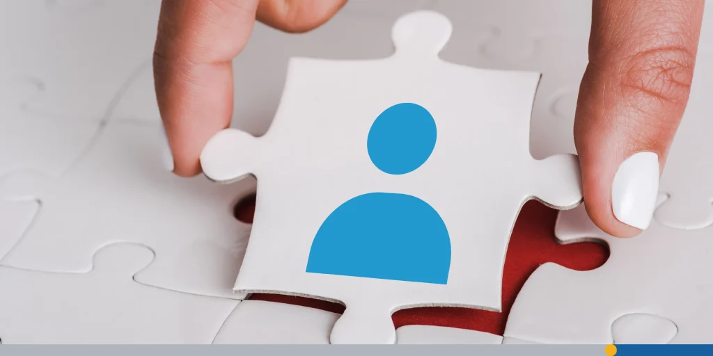 Close up of woman holding white jigsaw with blue human icon near connected puzzle pieces