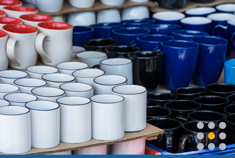Focus on foreground of many various ceramic mugs display for sale at outdoor market