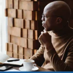 Man looking out a window thinking about a blog name idea