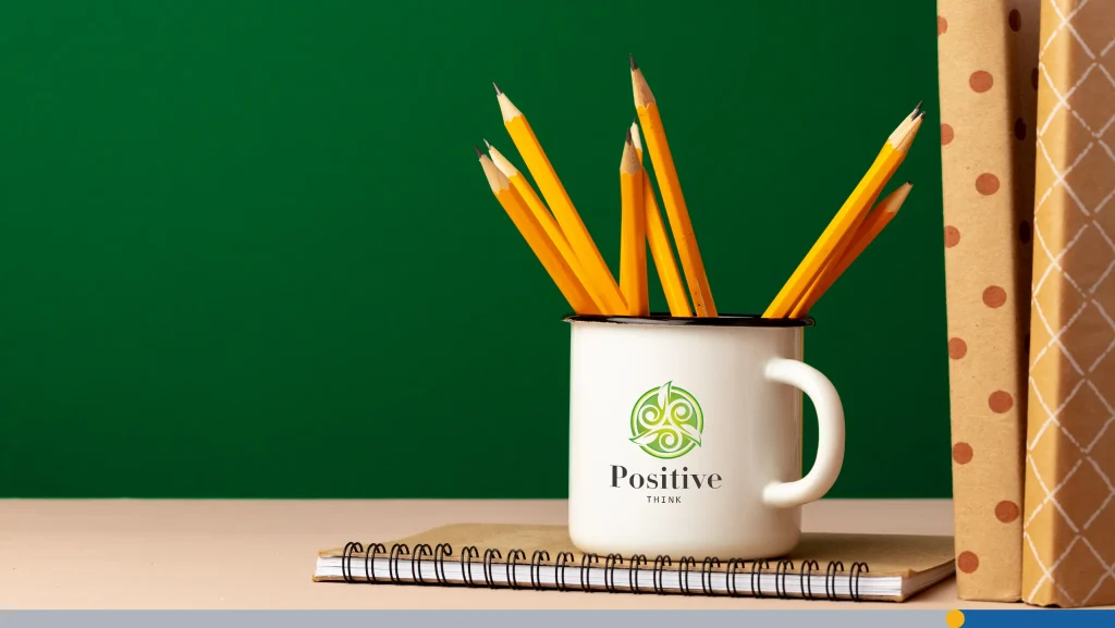 School supplies on wooden desk against green chalkboard