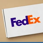 White paper rectangular box on beige background with the FedEx logo on it