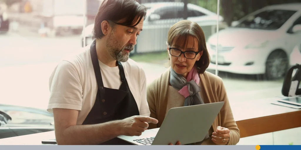 A friendly middle aged barista and a senior businesswoman collaborate