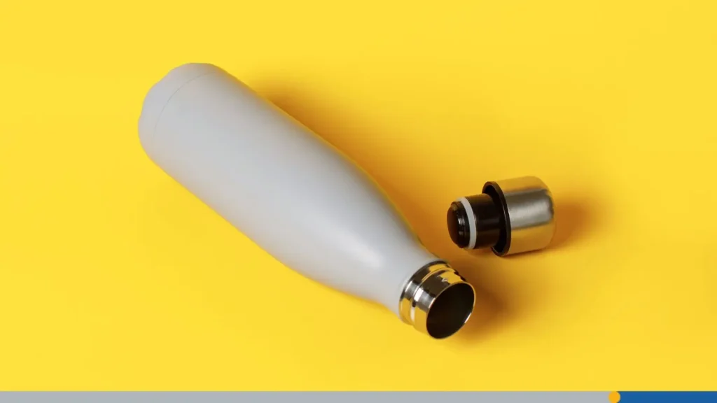 Grey reusable insulated bottle on yellow background.