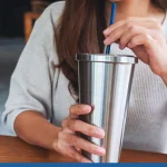 Woman holding a tumbler reading a custom drinkware guide
