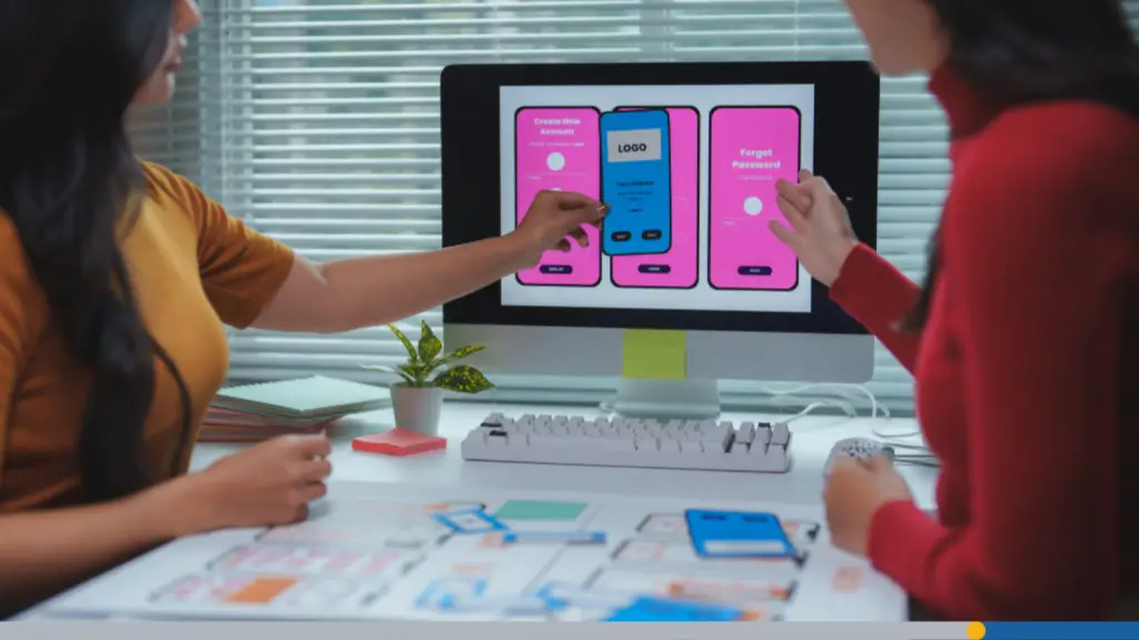 Two web designers collaborate at a desktop computer, planning how to build a brand online with a custom site.