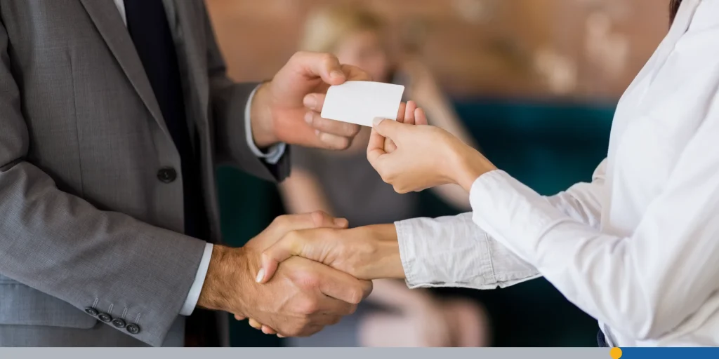 A typical business card transaction with a handshake and a business card exchanging hands.