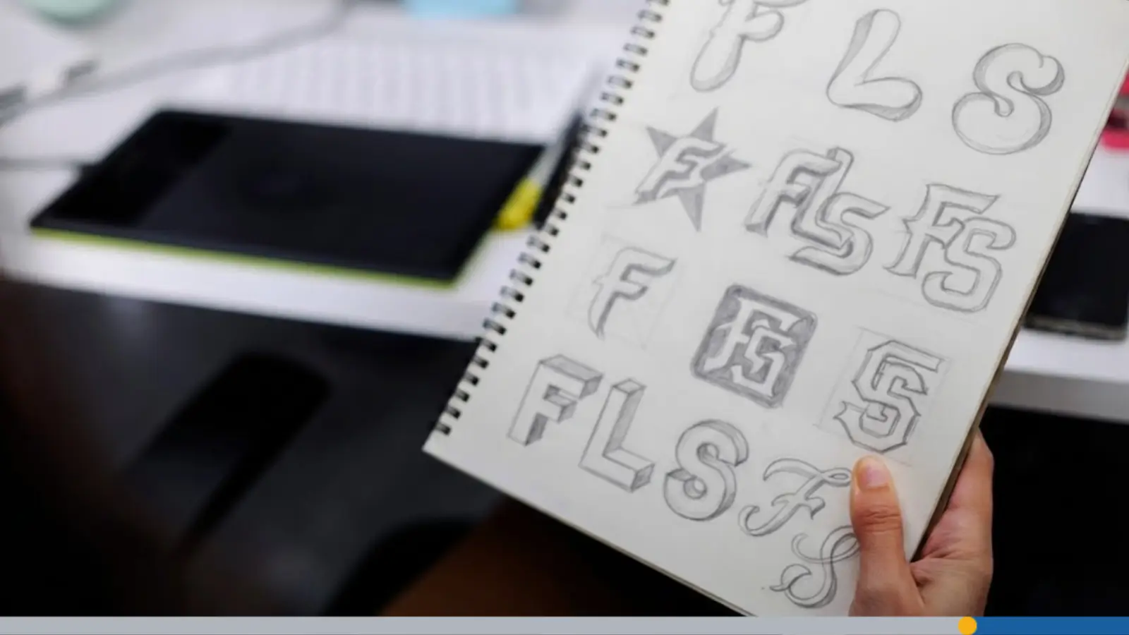 An artist sketching three letters in a journal as a logo concept for personalized branding.