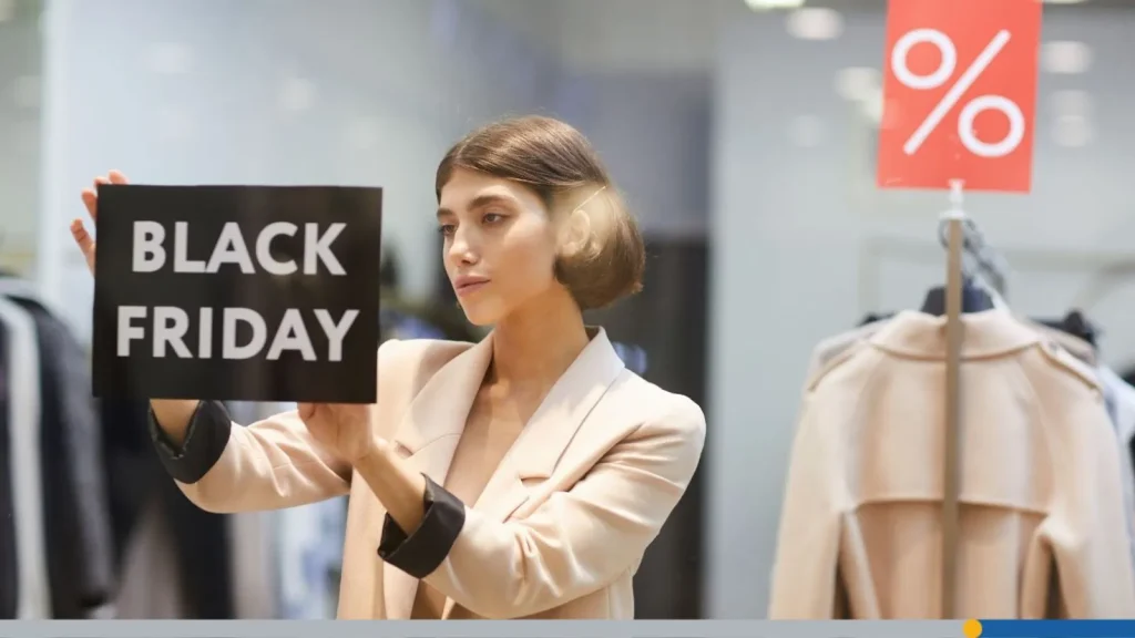 Retail employee placing a Black Friday sign in a clothing store