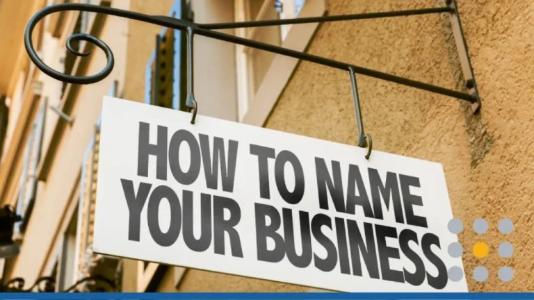 A white hanging shop sign mounted on a textured building wall featuring bold black text that reads "HOW TO NAME YOUR BUSINESS".