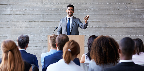 man in suit giving speech to a crowd