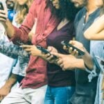 a group of young adults all on their cell phones