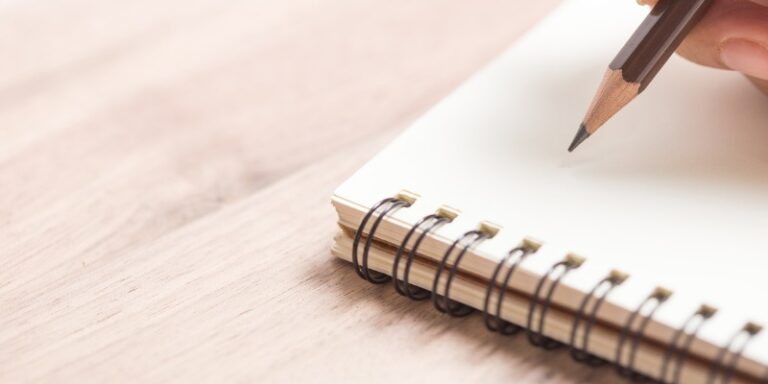 hands writing on a notebook with a pencil