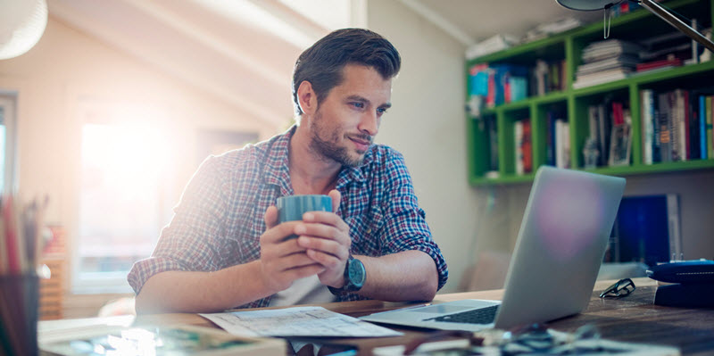 man sitting at desk looking at his laptop