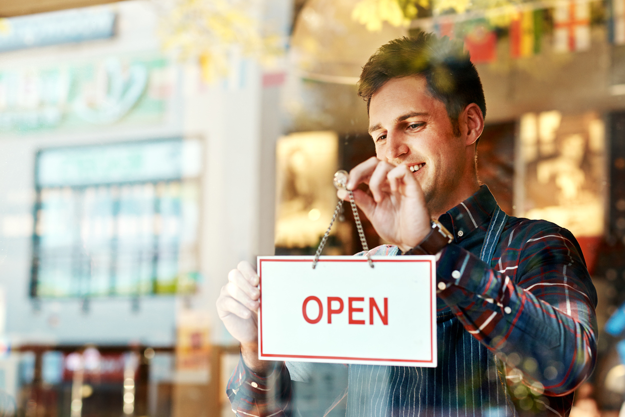 young man hanging up Open sign