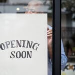 Man putting on store opening soon sign